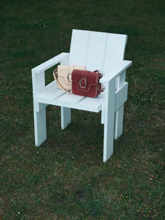 Sacs à main en cuir beige et rouge de Becksöndergaard, posés sur une chaise en extérieur, disponibles à Divonne.