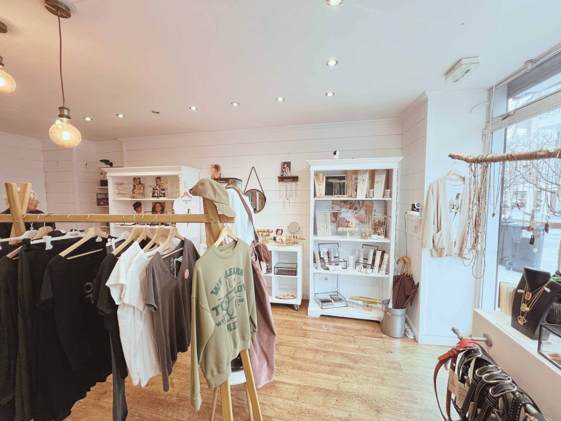 Intérieur de la boutique Moi d'Abord à Divonne-les-Bains, avec une sélection de vêtements, bijoux et accessoires.">