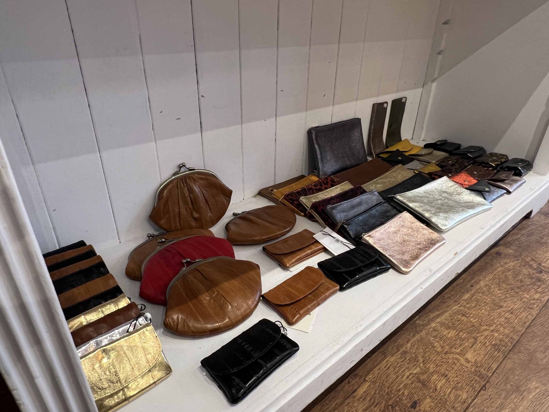 Collection de pochettes et porte-monnaie en cuir dans différentes teintes et finitions, disponibles chez Moi d'Abord à Divonne-les-Bains.
